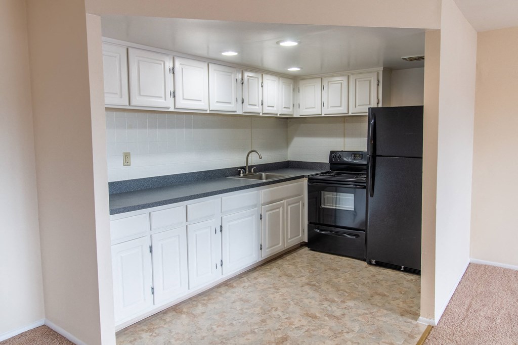 a kitchen with white cabinets and a black refrigerator