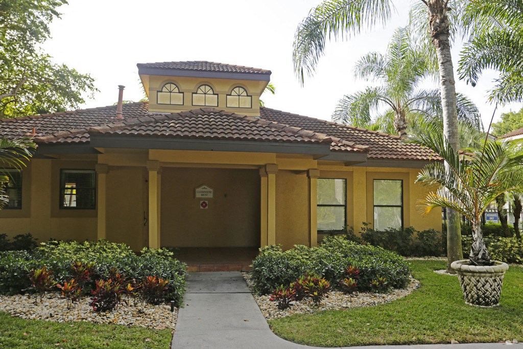 a yellow house with a sidewalk and palm trees