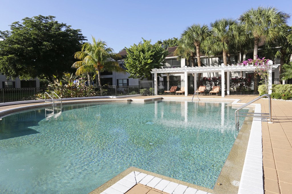 a large swimming pool in front of a house with palm trees