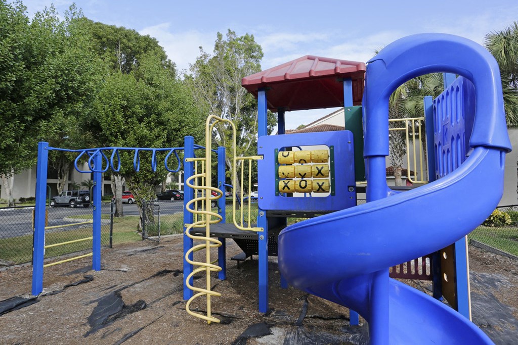 a playground with a blue slide and a red roof