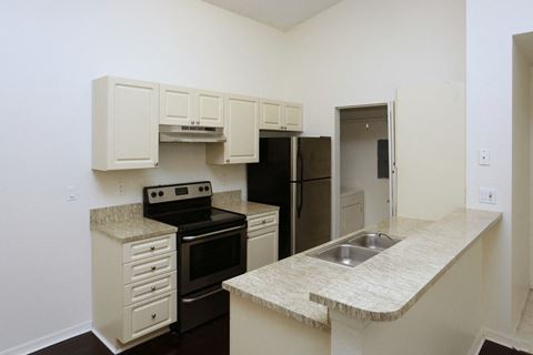 an empty kitchen with white cabinets and black appliances