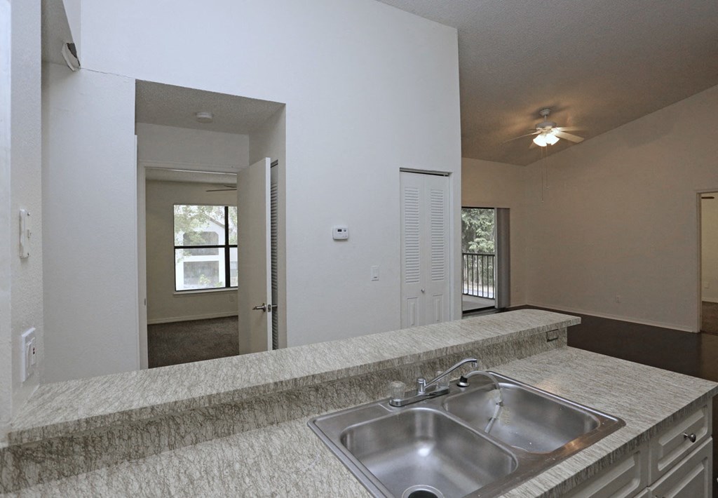 an empty kitchen with a sink and a large mirror