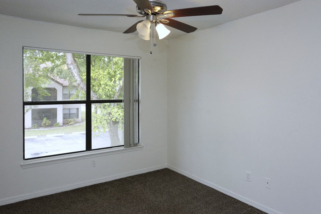 a bedroom with a large window and a ceiling fan