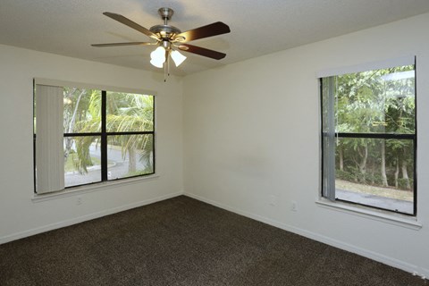 a living room with a ceiling fan and large windows