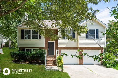 a white house with a garage door and a tree