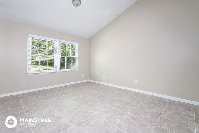 the living room of a home with a tiled floor and a window