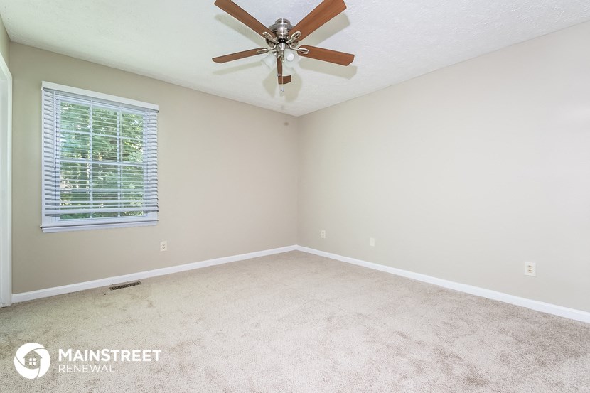the master bedroom has a carpeted floor and a ceiling fan