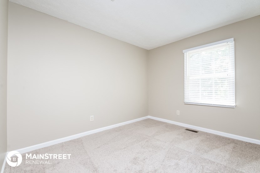 the upstairs bedroom has a large window and tile flooring
