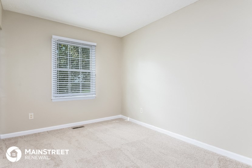the upstairs bedroom has a carpeted floor and a window