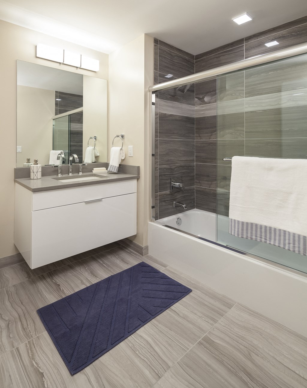 a bathroom with a shower and a sink and a blue rug