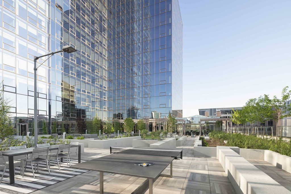 an outdoor patio with tables and chairs in front of a tall building