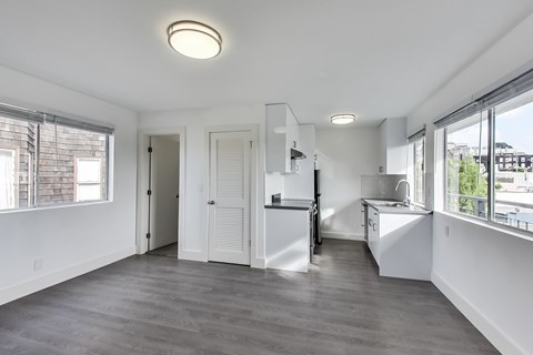 A spacious kitchen with white cabinets and a large window.