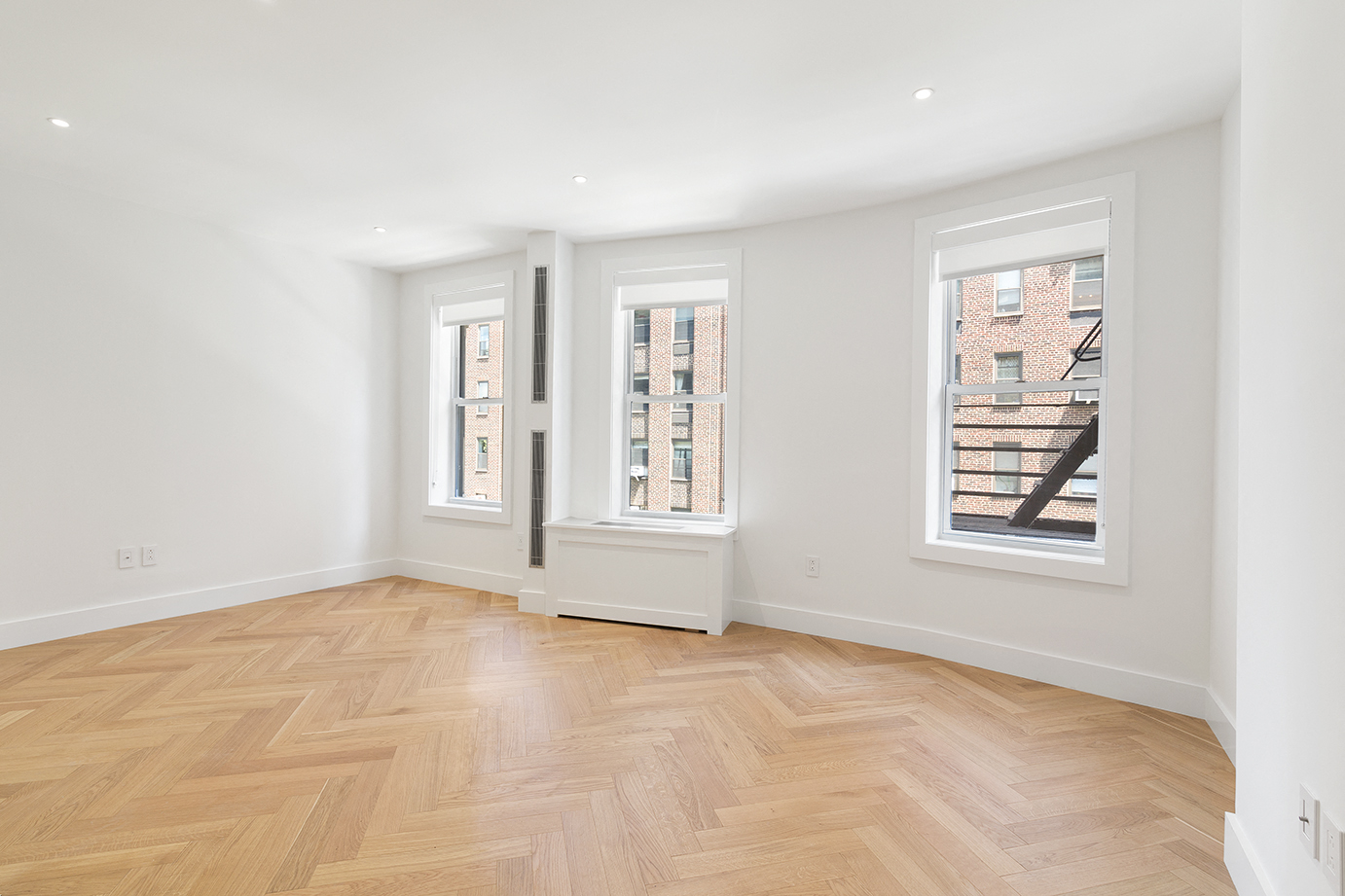 a living room with a hardwood floor and three windows