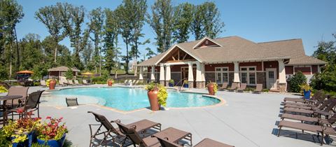 a swimming pool in front of a house with patio furniture