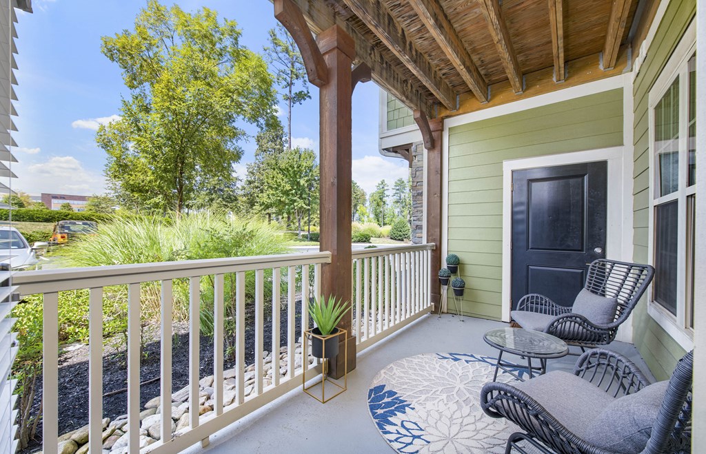 a porch with two chairs and a table and a black door