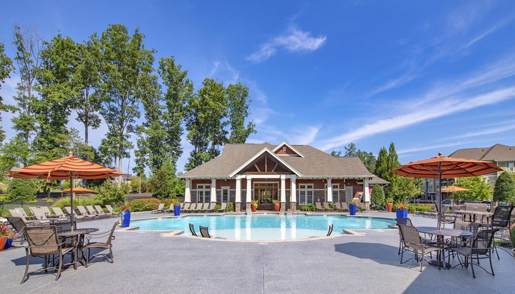 a swimming pool with chairs and umbrellas in front of a house