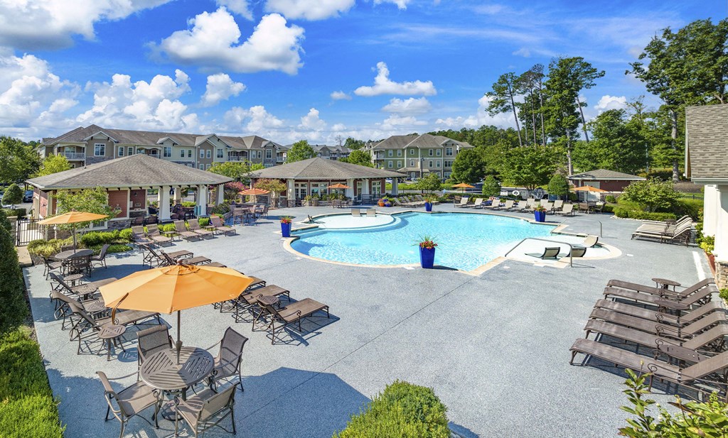 an aerial view of a swimming pool with patio furniture and umbrellas