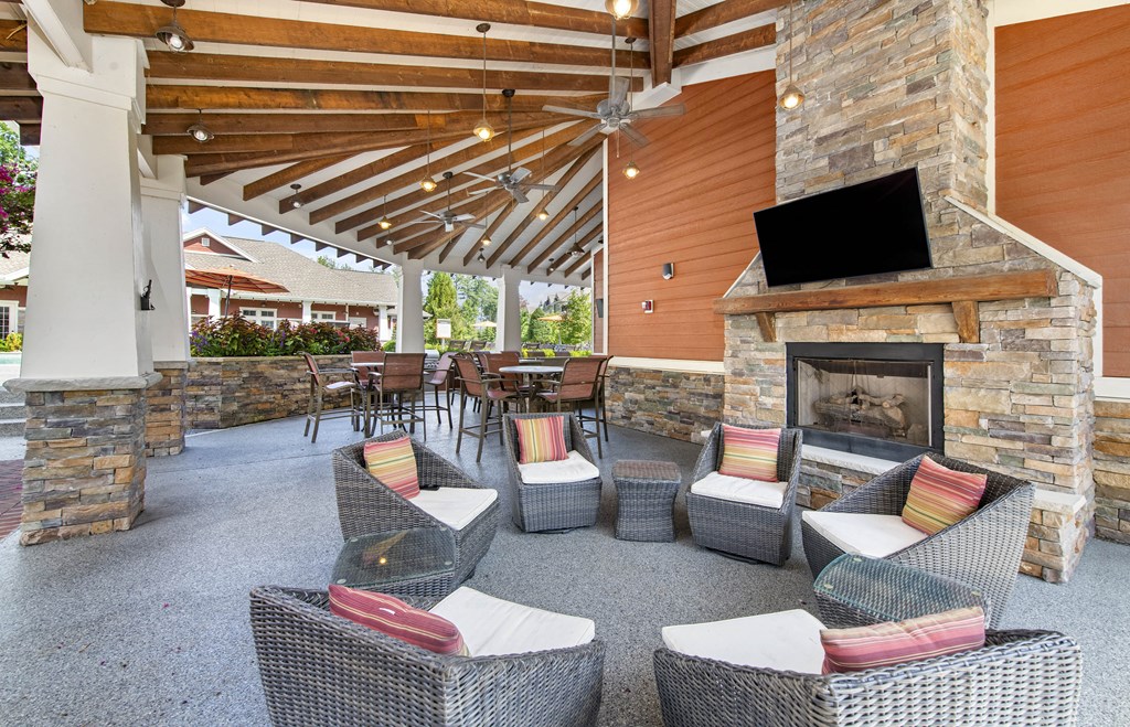 a covered patio with a fireplace and chairs