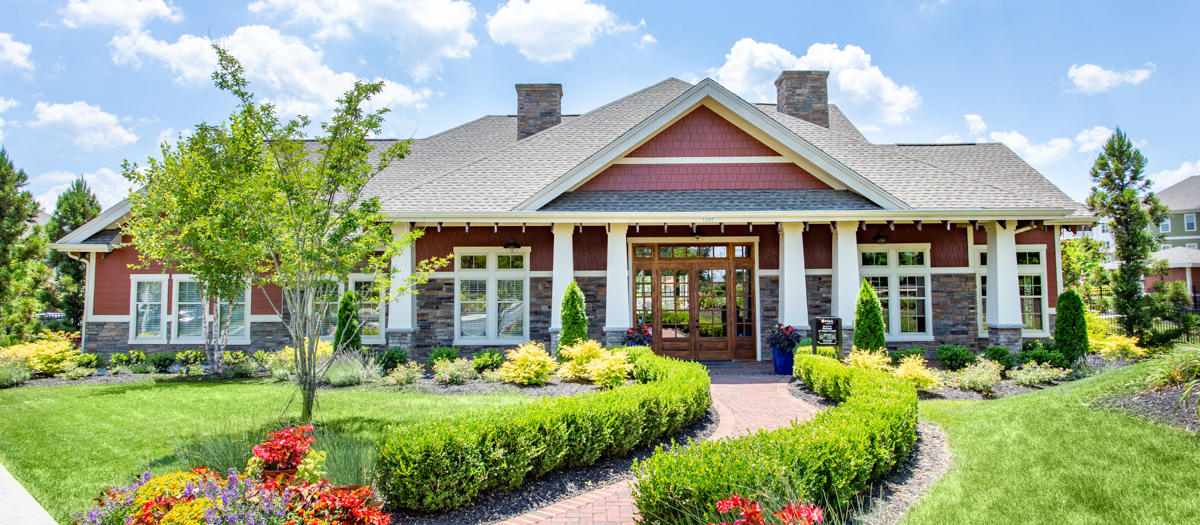 the front of a house with a manicured lawn and a garden