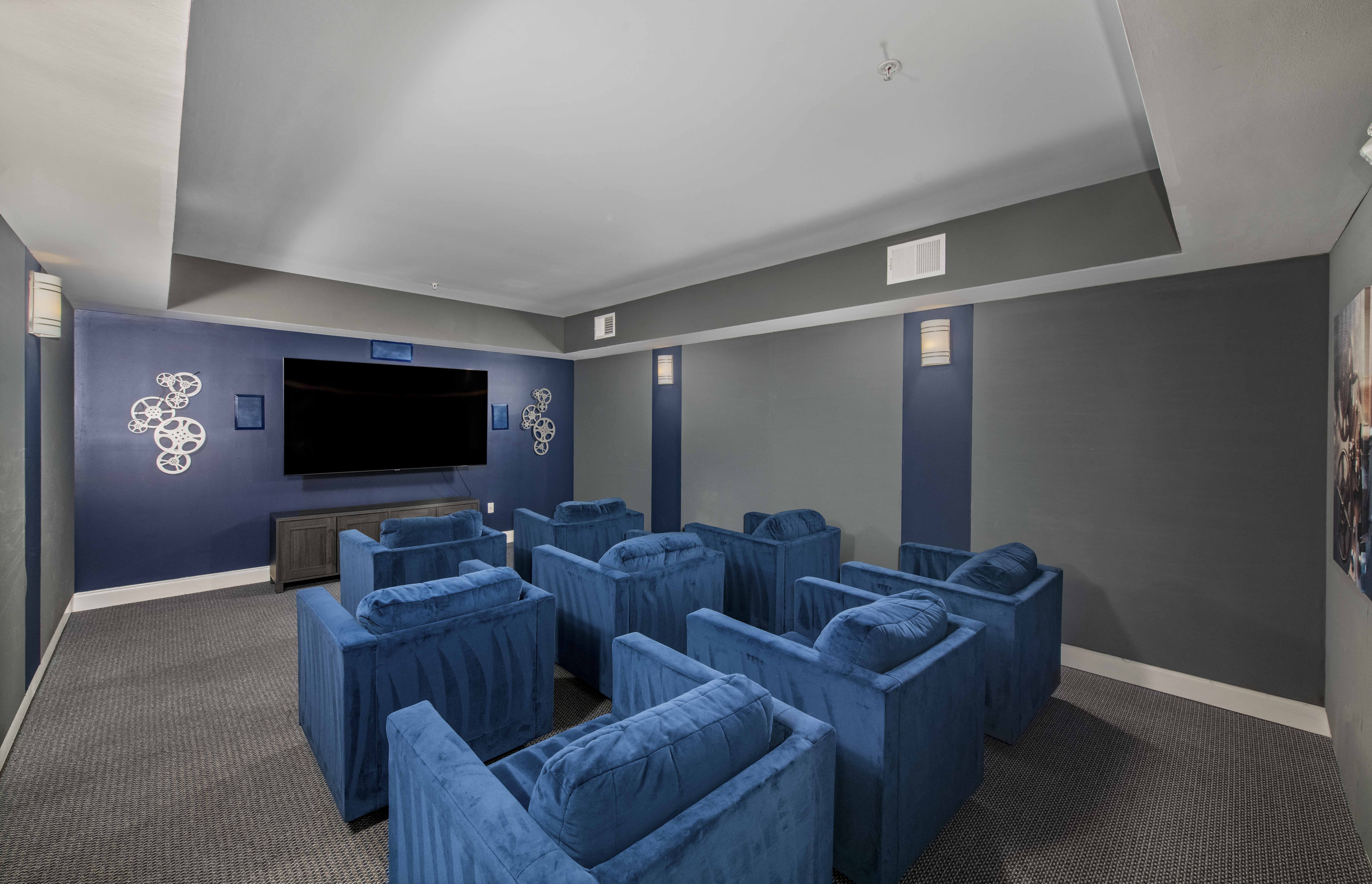 a small screening room with blue chairs and a television