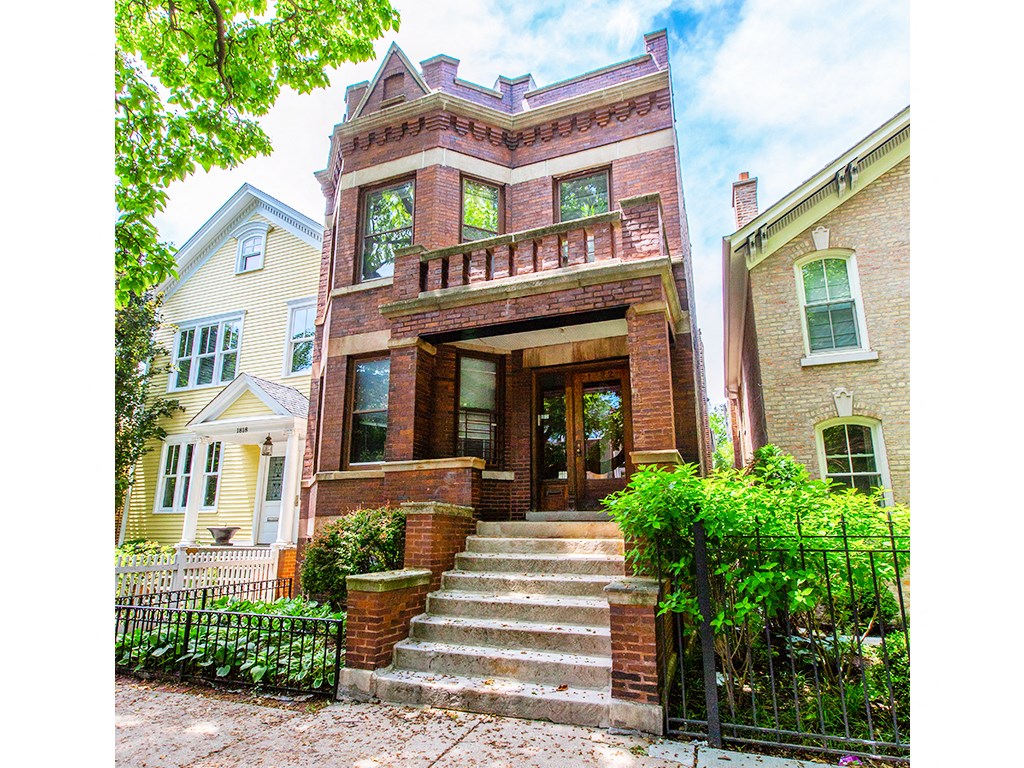 the front of a brick house with stairs and a gate