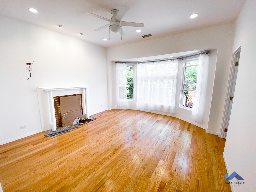 an empty living room with wood floors and a ceiling fan
