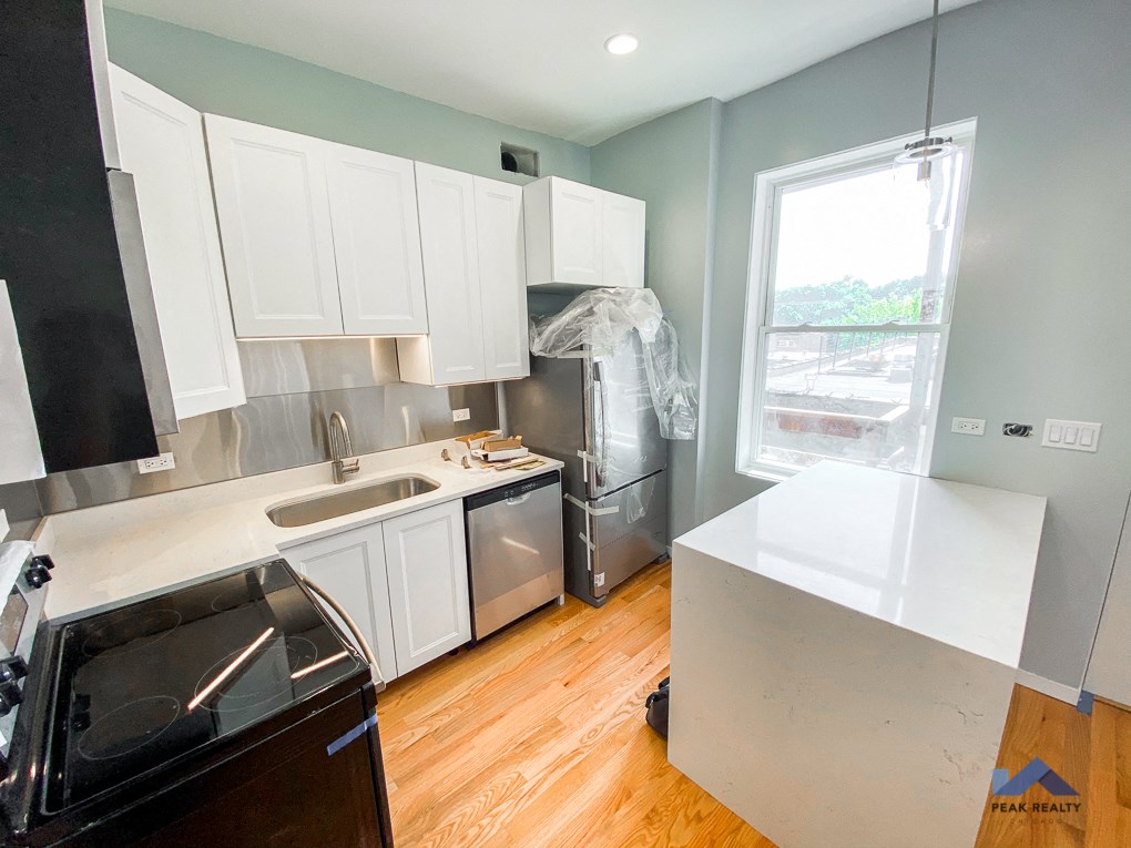 a kitchen with white cabinets and stainless steel appliances and a window