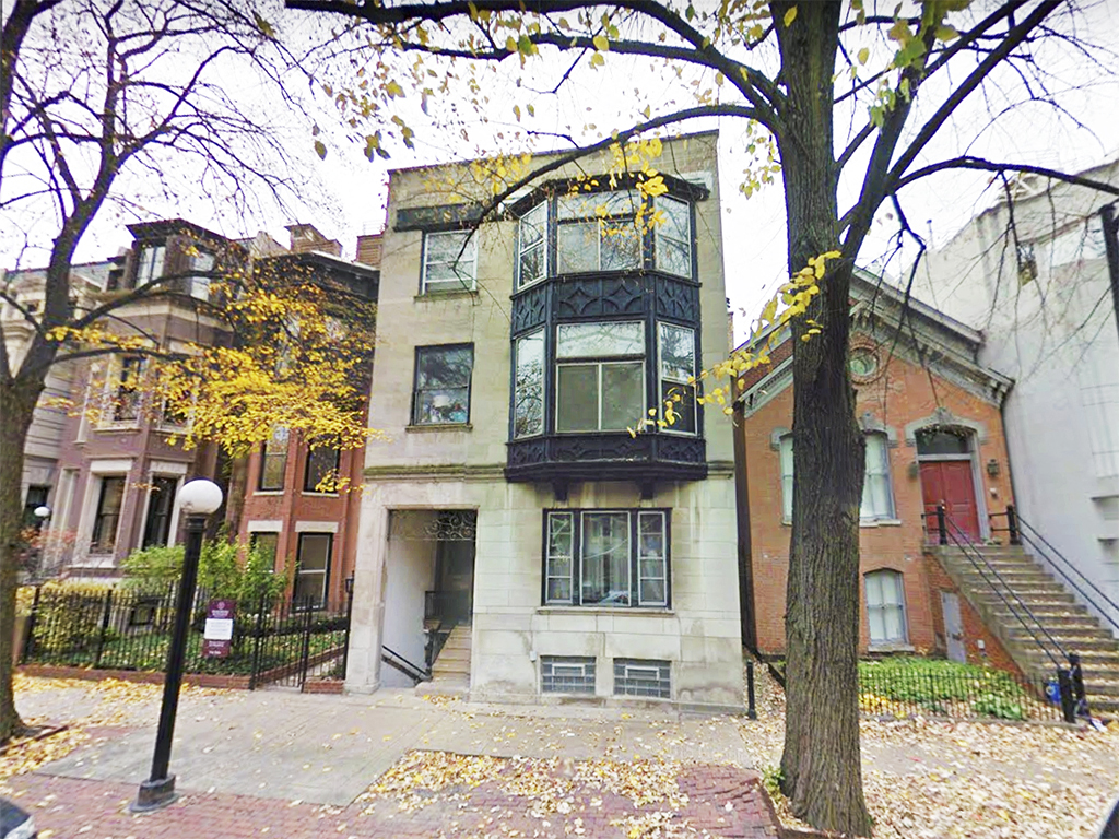 a house with a black balcony on a city street