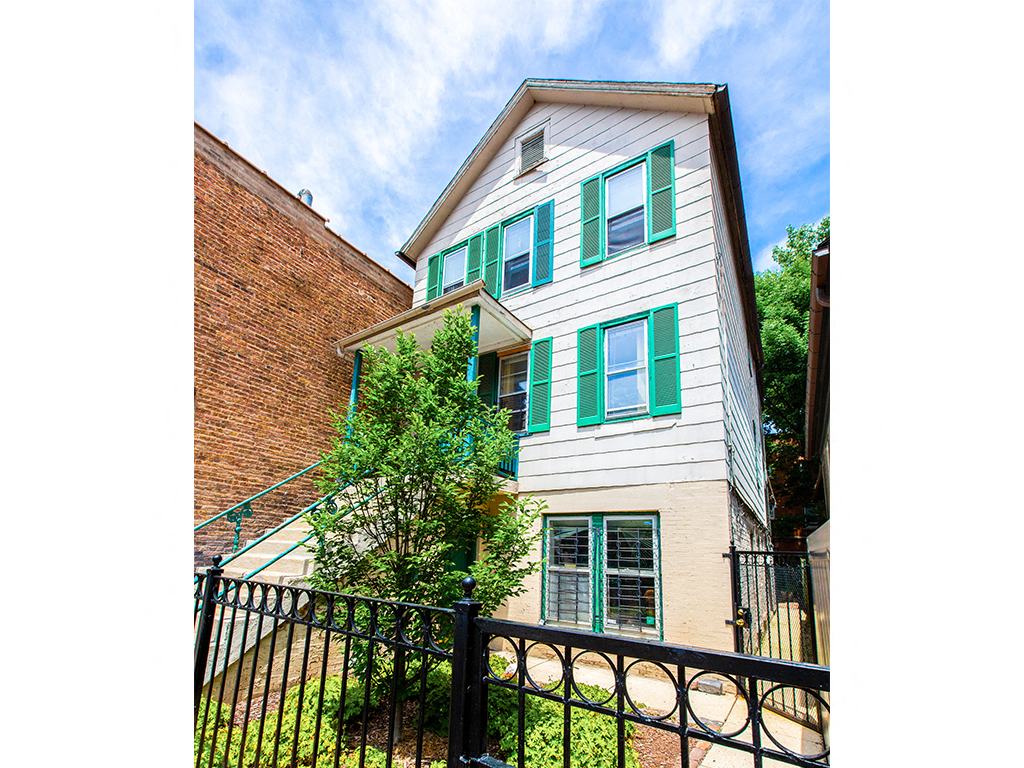 A house with green shutters and a black fence.