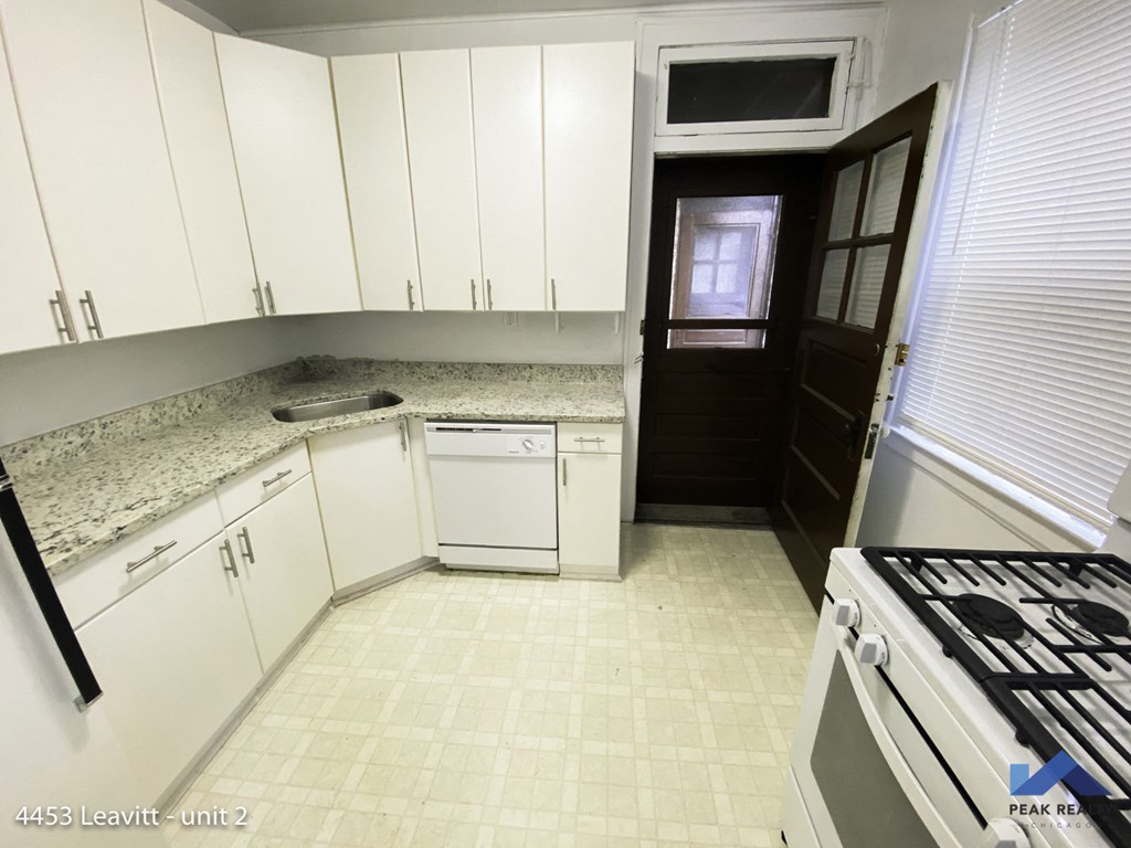 an empty kitchen with white cabinets and a stove top oven