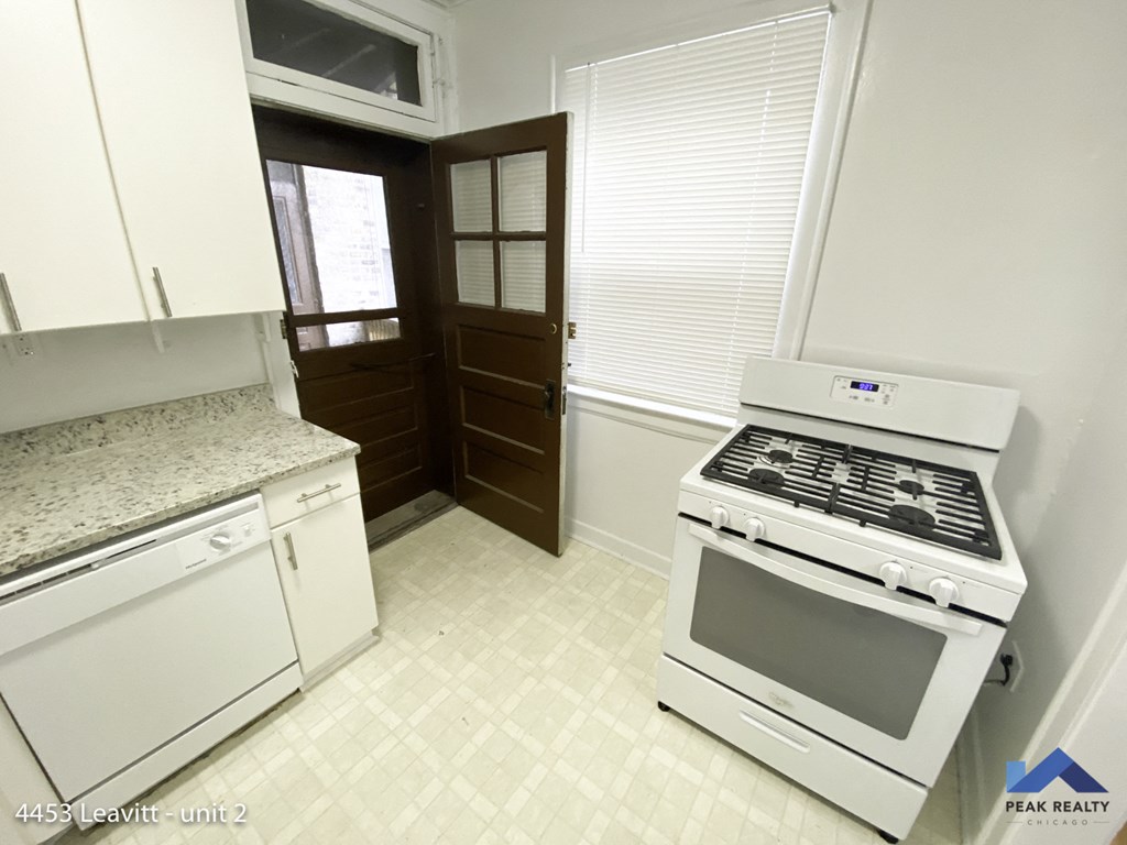 a kitchen with white appliances and a stove and a door