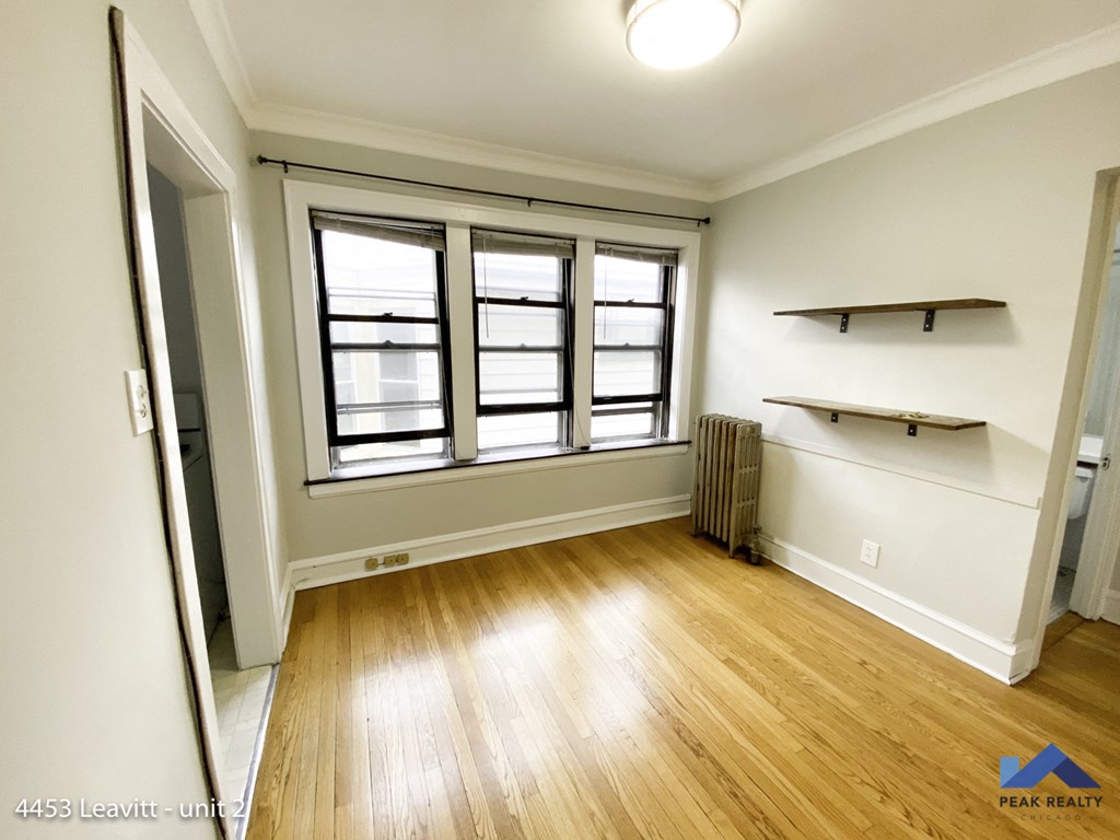 an empty living room with wood flooring and windows