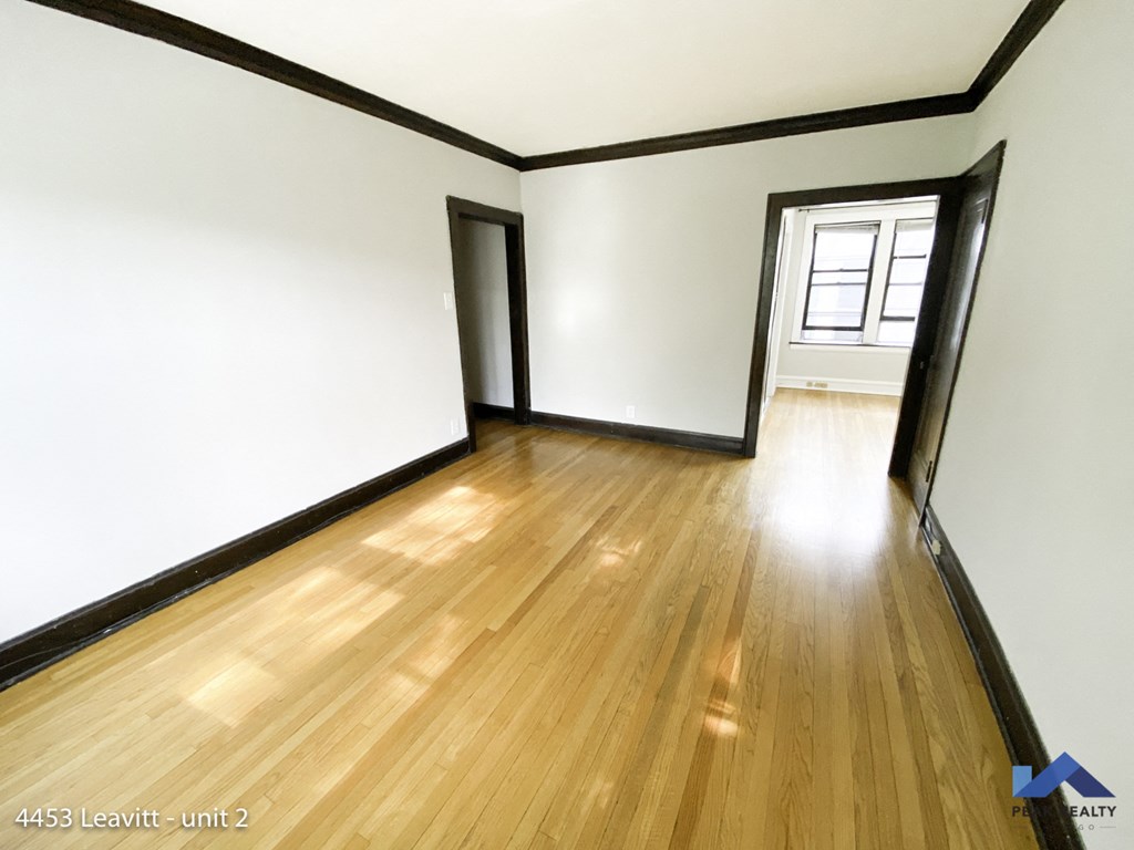 an empty living room with wood floors and white walls