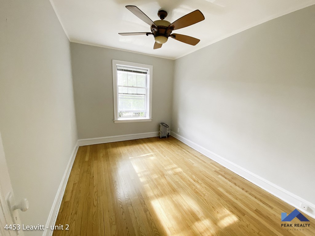 an empty room with wood floors and a ceiling fan