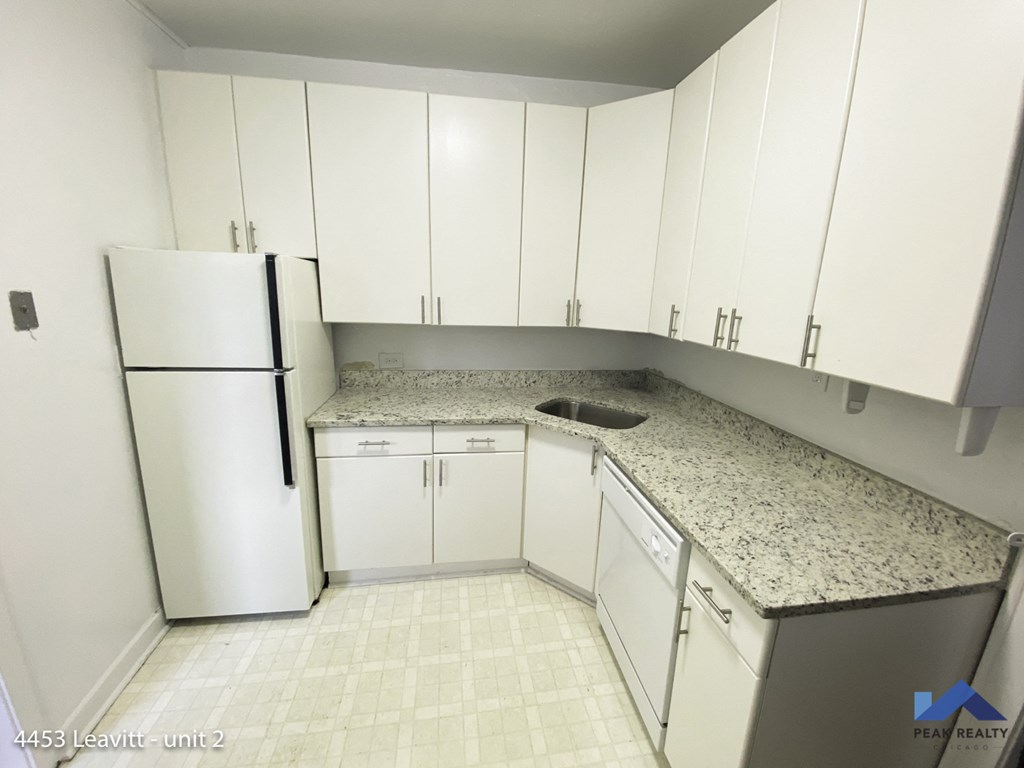 an empty kitchen with white cabinets and granite counter tops