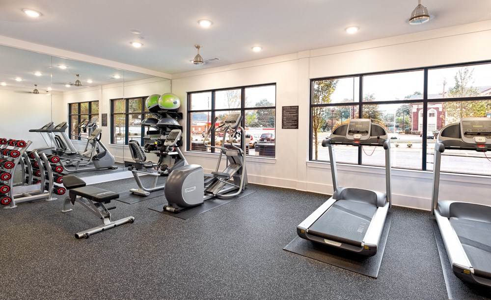 a gym with treadmills and other exercise equipment and windows