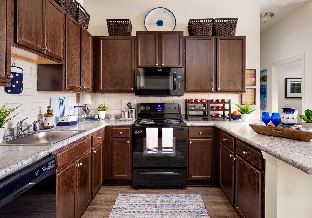 a large kitchen with dark wood cabinets and black appliances