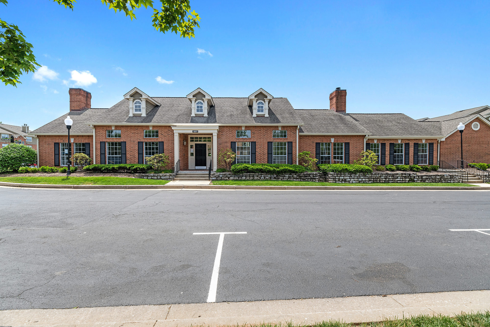 the front of a large brick house with an empty parking lot