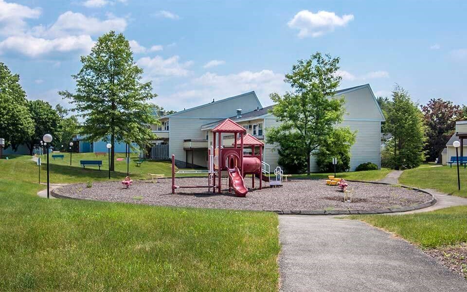 a playground in a park with a sidewalk