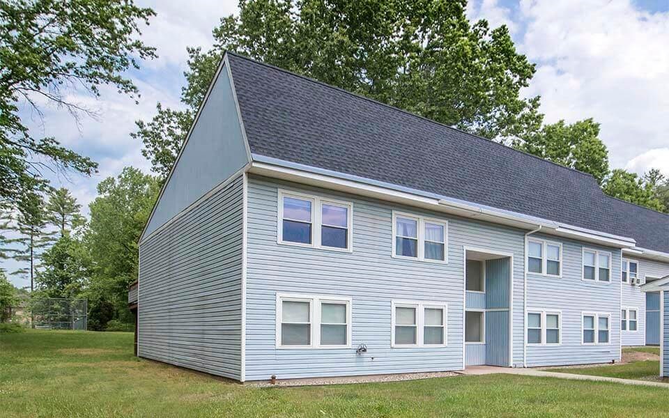 a blue house with a gray roof and a lawn