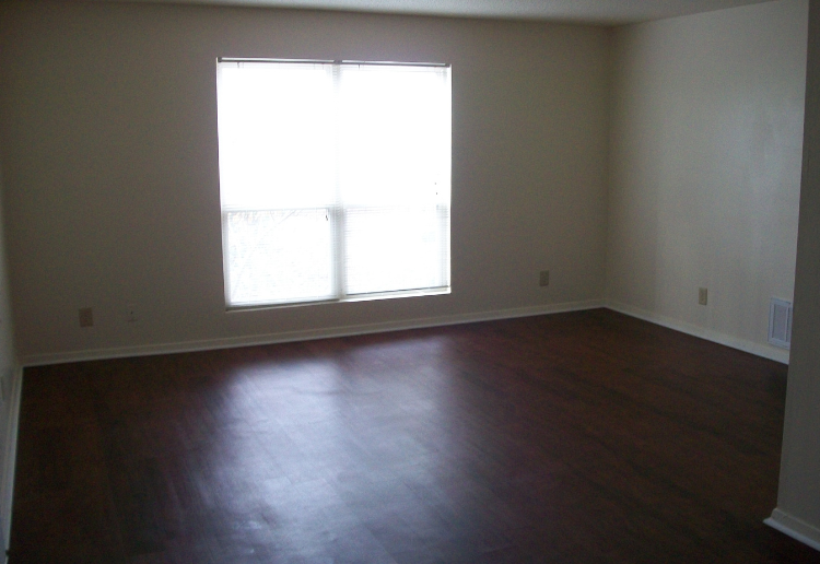 an empty living room with wood floors and a window