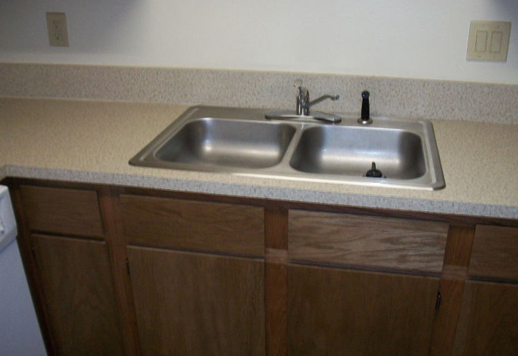 a sink in a kitchen with wooden cabinets