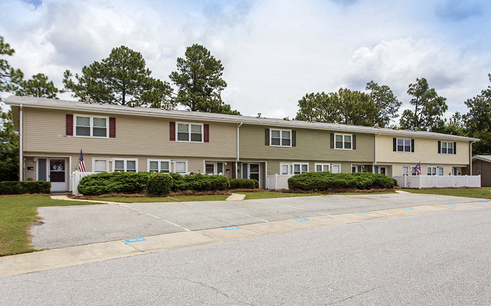 the front of an apartment building with a parking lot