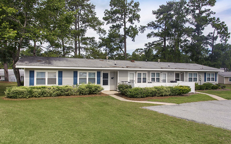a white house with blue shutters and a lawn