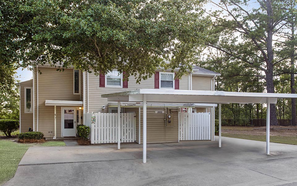 a yellow house with a white porch and a driveway
