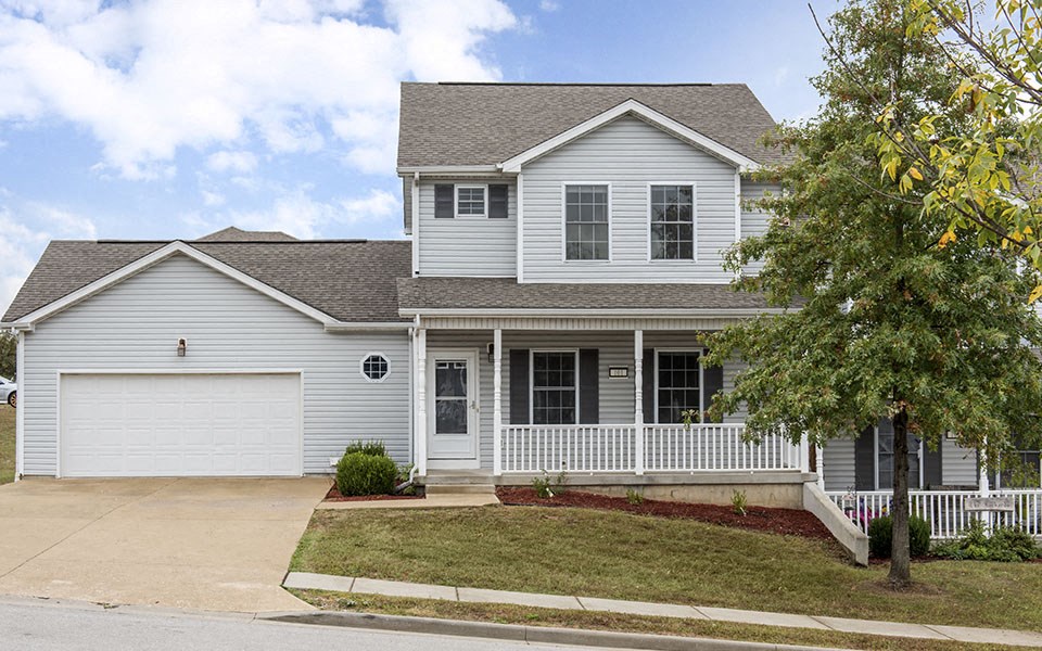 a white house with a porch and a white garage door