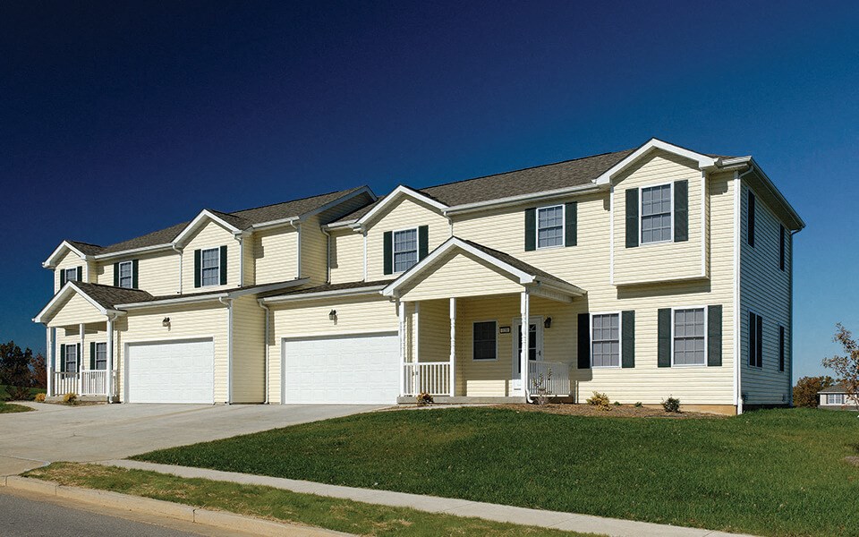 a yellow house with white garage doors