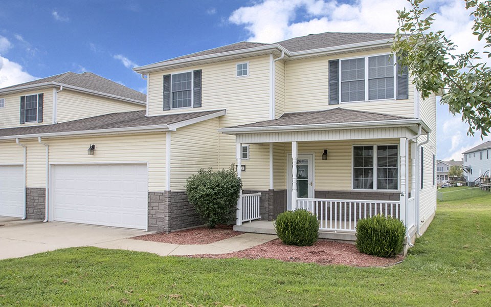 a yellow house with a front porch and a lawn