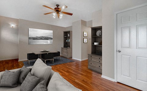 a living room with a couch and a desk and a ceiling fan