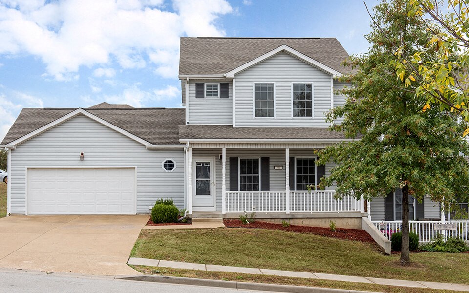 a white house with a porch and a white garage door